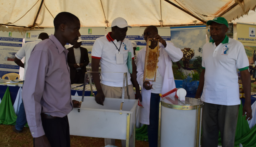 Edward Alitsi, VCDO Executive Director (R) onlooking as one of VCDO Staff exhibiting what they do in Beekeeping during Nile Day 2016/ Photo NBD