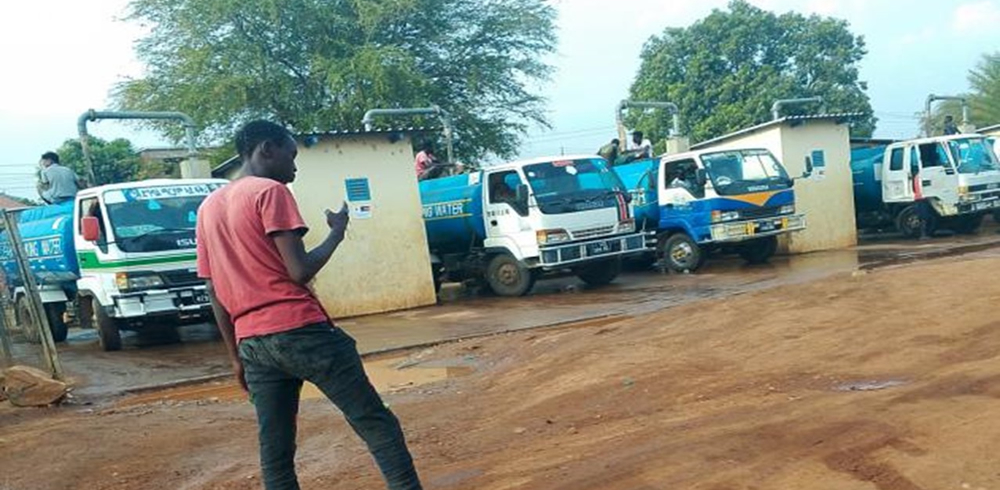 Water tanker trucks line up at a distribution point to fill treated water for supply